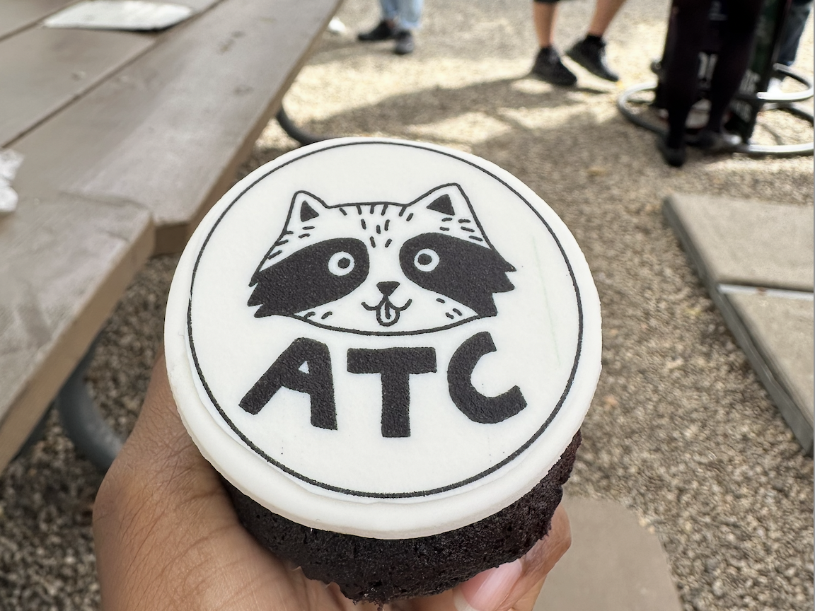 Chocolate cupcake topped with an ATC raccoon stamp at a community gathering
